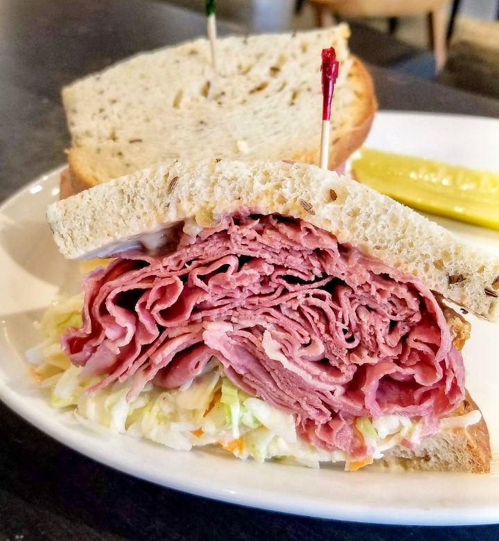 Corned beef sandwich on rye with coleslaw and pickle