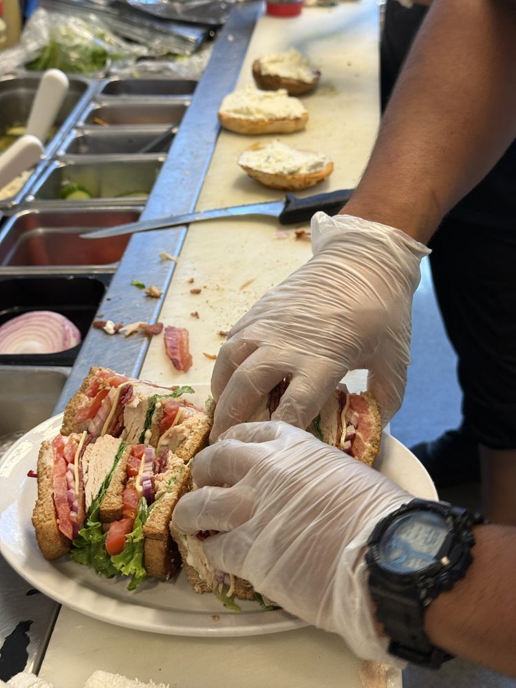 Gloved hands building a triple-decker sandwich