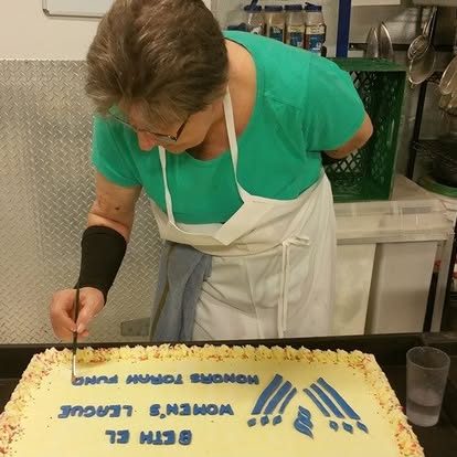 A team member decorating a sheet cake for Beth El Women's League