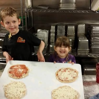 Two kids showing off their pizza bagels