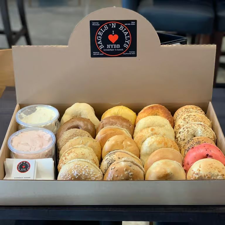 A box of assorted NYBB bagels with cream cheese, ready to take home